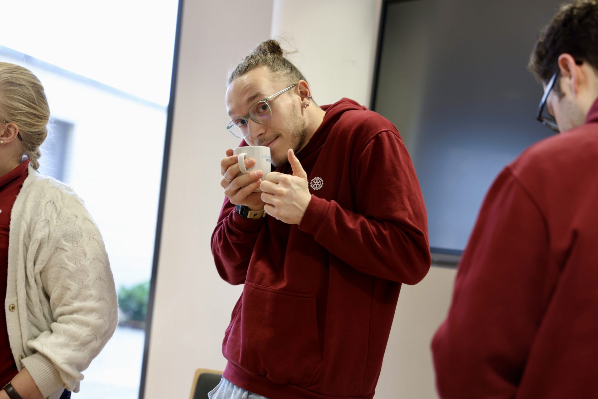 RDK Sitzung Paderborn Bene mit Kaffee Mann in dunkelroter Sweatjacke hält eine Kaffeetasse und hält einen Daumen hoch.