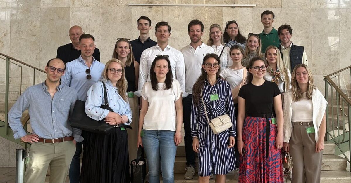 RotaractNews 20 Rotaracter*innen stehen auf einer Treppe im Gebäude und lächeln in die Kamera.